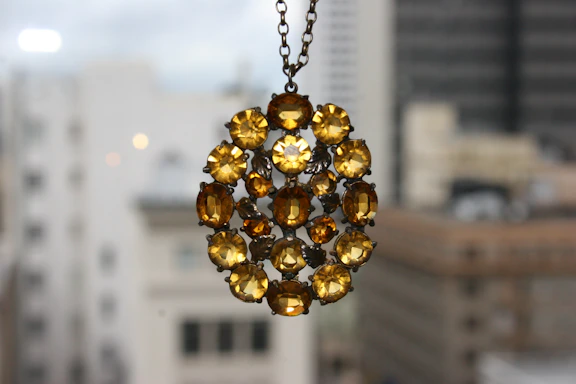 Elegant pendant necklace featuring a polished amber stone hanging against a blurred natural background.