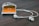 A smartphone with a visible orange screen displaying the Google Play app icon rests on a wooden surface. Earphones connected to the phone are neatly positioned beside it.