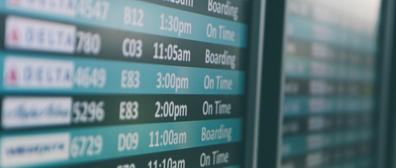 Airport departures timetable showing Delta and Alaska Airlines flights on time and boarding