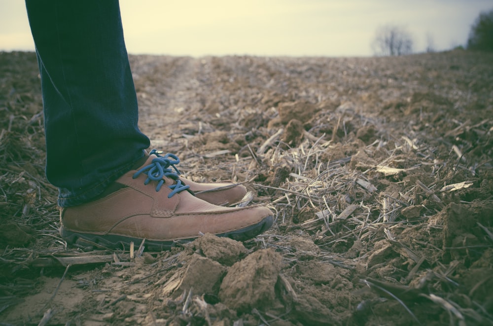 pessoa em pé usando sapatos de couro marrom durante o dia