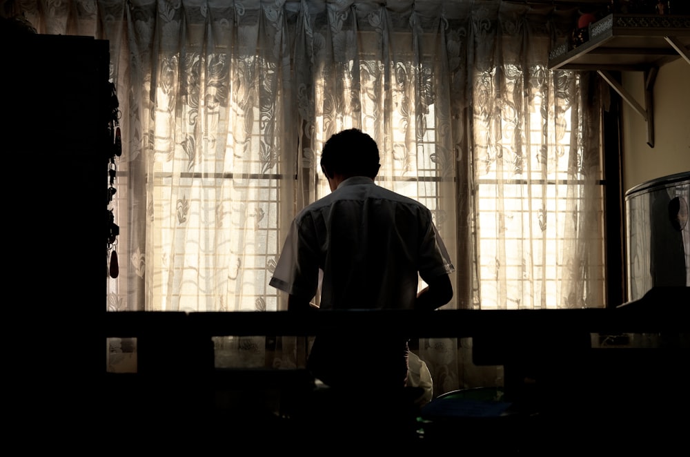 man wearing white collared shirt near window