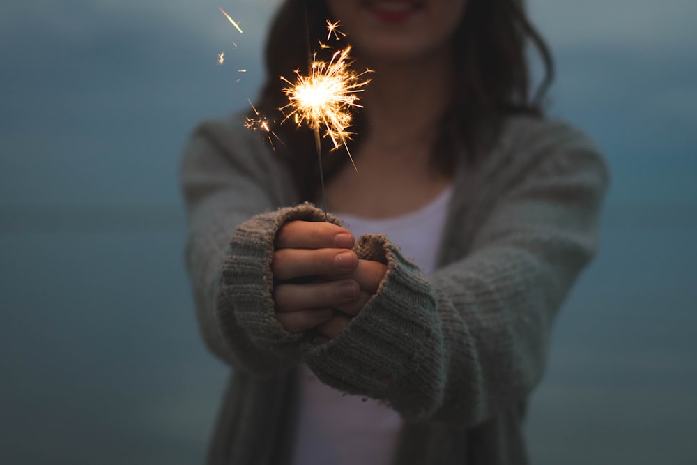 focus photo of a woman holding sparklers