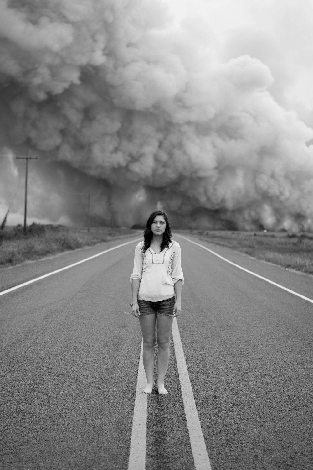 도로 한가운데에 서 있는 여자의 회색조 사진