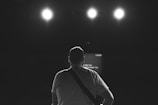 Silhouette of a musician holding an acoustic guitar on stage.