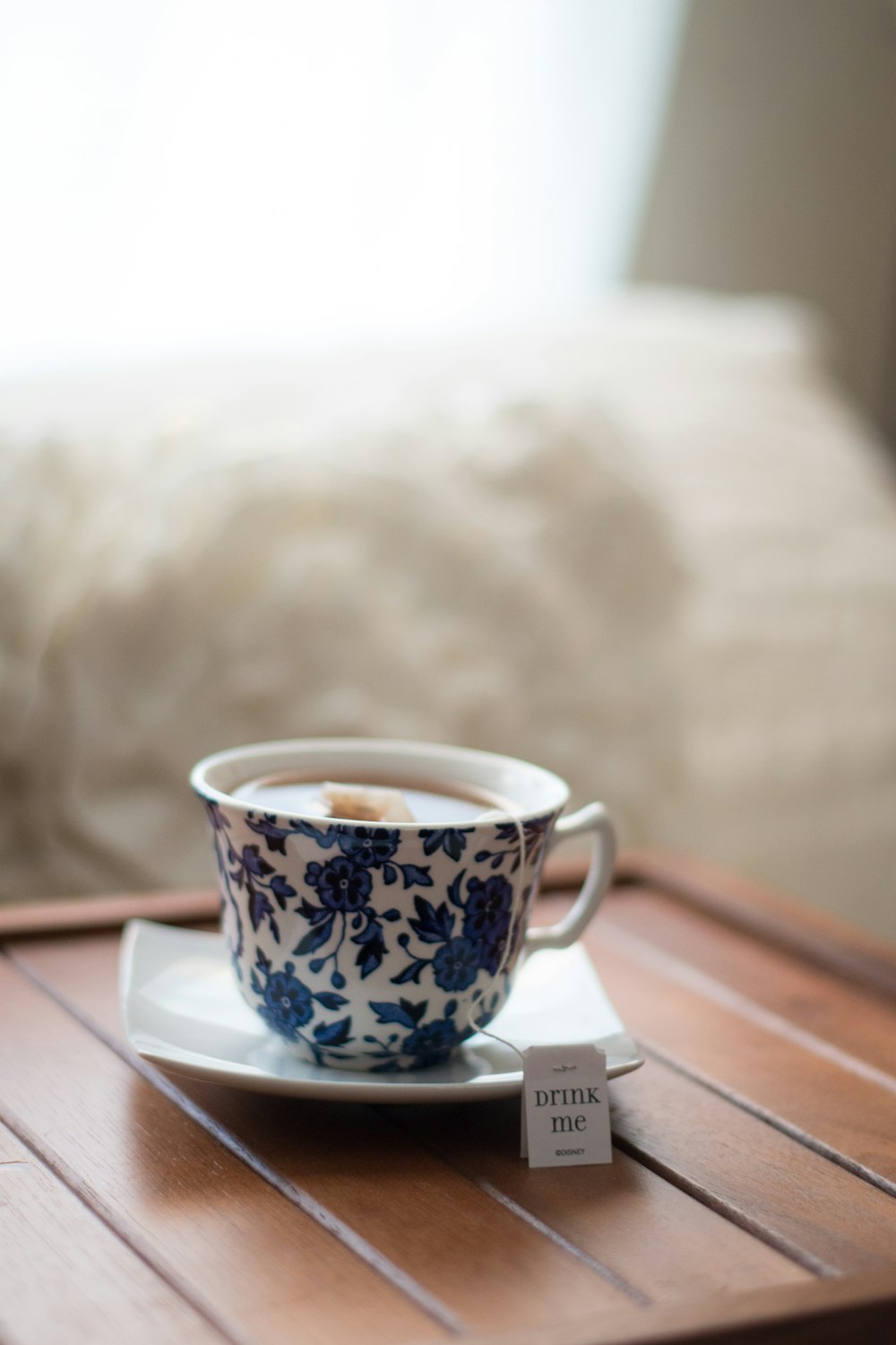 Weiße und blaue geblümte Teetasse mit Teebeutel in Untertasse in Tilt-Shift-Fotografie