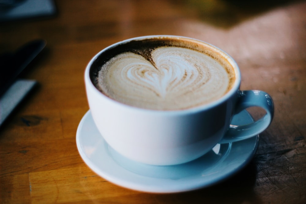 cup of cream coffee on brown surface