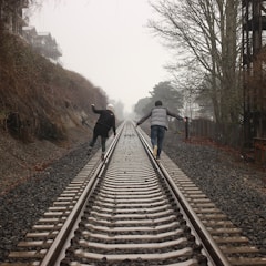 two person walking on the train rail