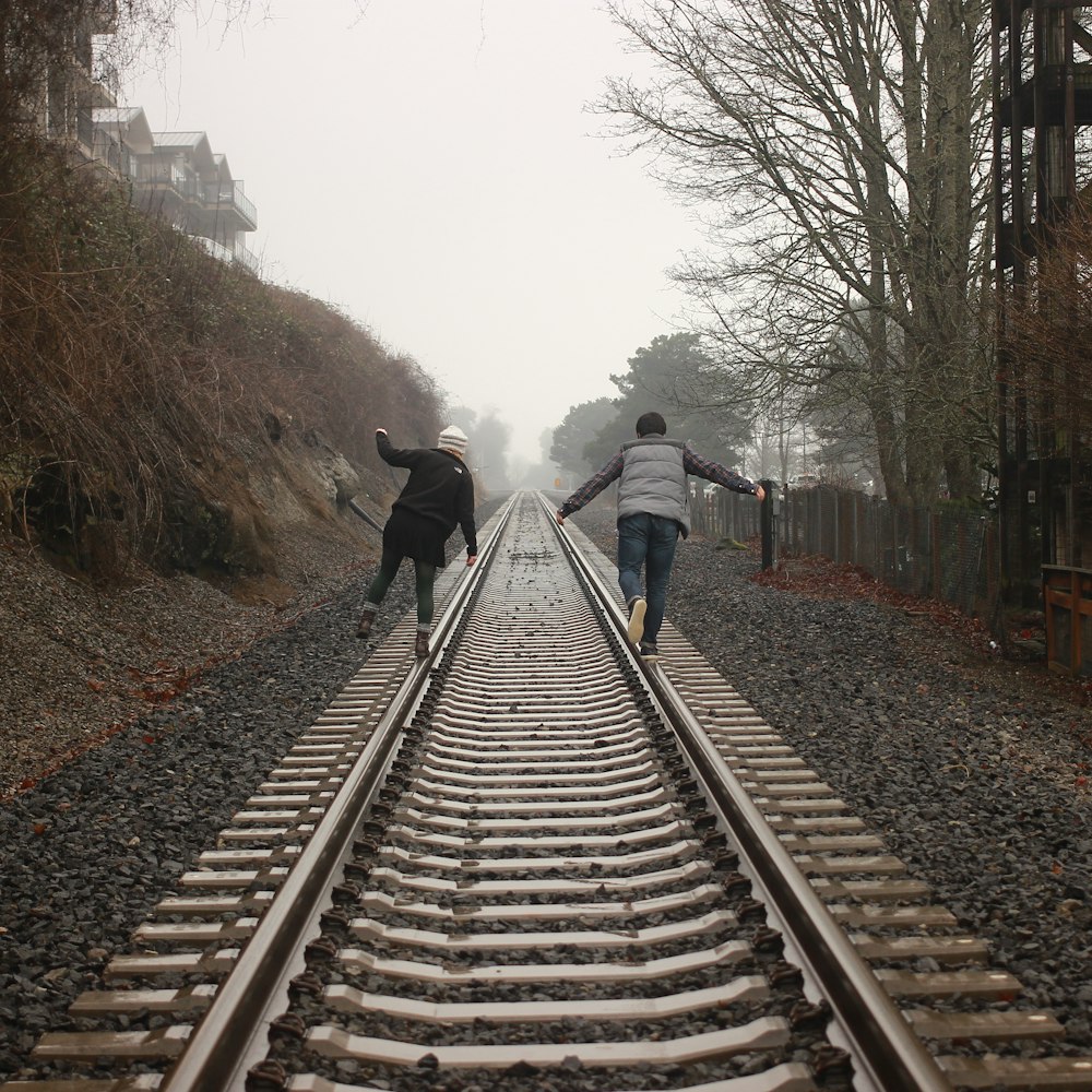 電車のレールの上を歩く2人