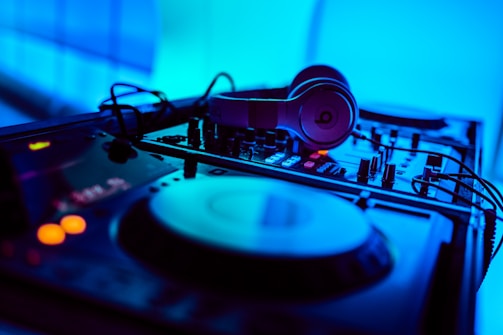 Close-up shot of headphones resting on a mixing console with glowing lights.