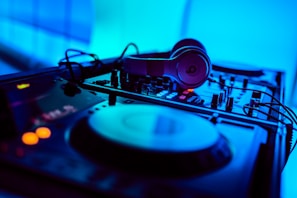 A close-up of headphones resting on a mixing console with colorful lights.