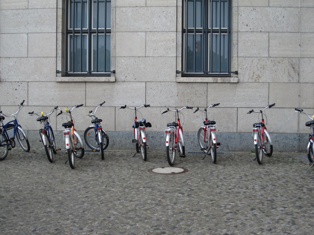 Bicicletas variadas estacionadas junto a la pared gris