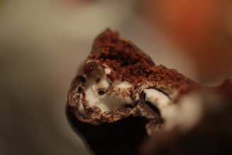 Close-up of a creamy cookies & cream cannabis chocolate square melting gently on a rustic wooden surface.