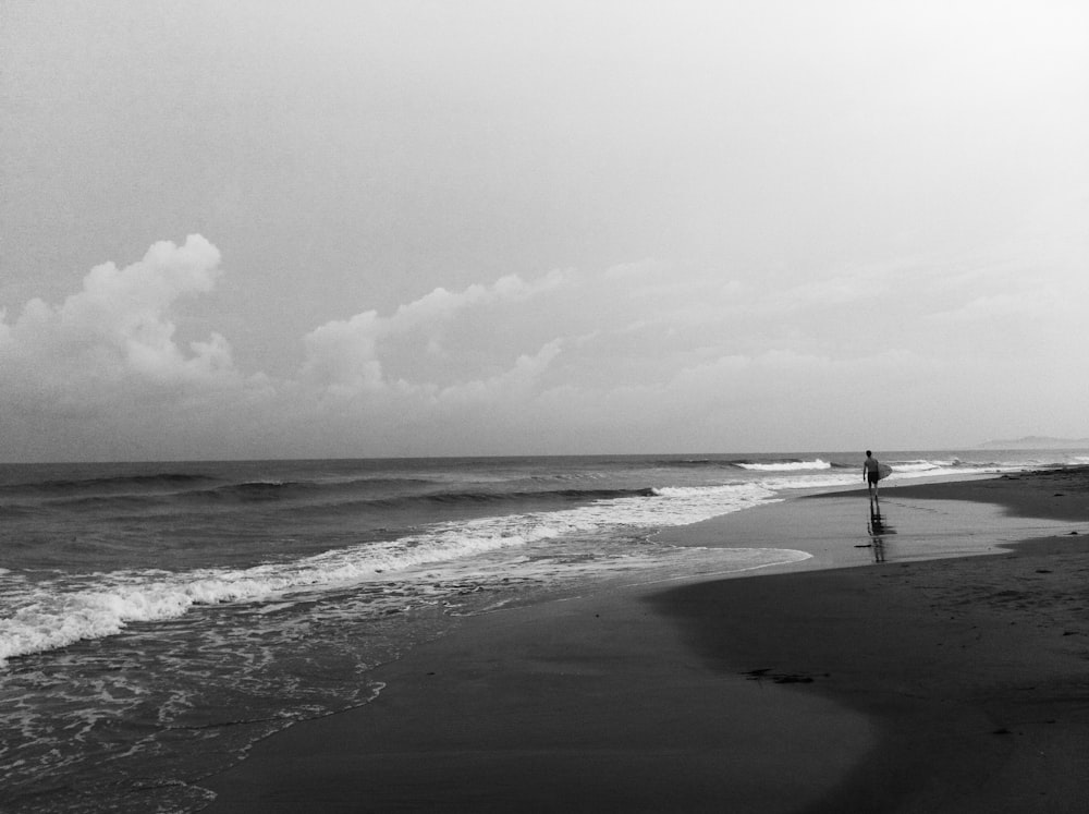 grayscale photography of person standing on seashore