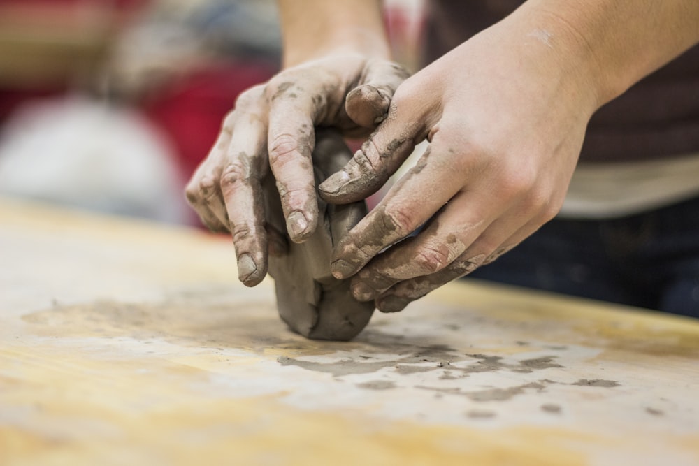 Uma mão manchada de barro de um oleiro que se dedica a um trabalho artesanal de cerâmica ou moldagem