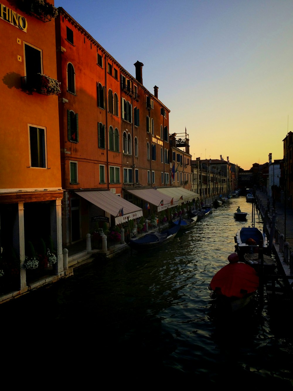 boats on canal near concrete buildings during daytime