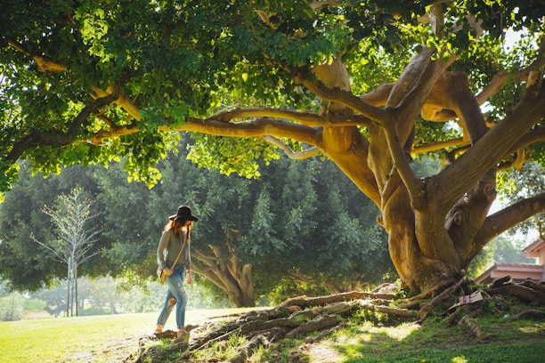 A young person wearing a stylish wool hat while walking through a leafy park on a crisp day.