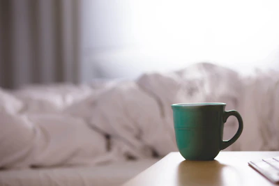 Close-up of a bright turquoise stoneware mug resting on a wooden table with soft morning light.