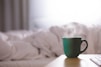 green ceramic mug on wooden desk