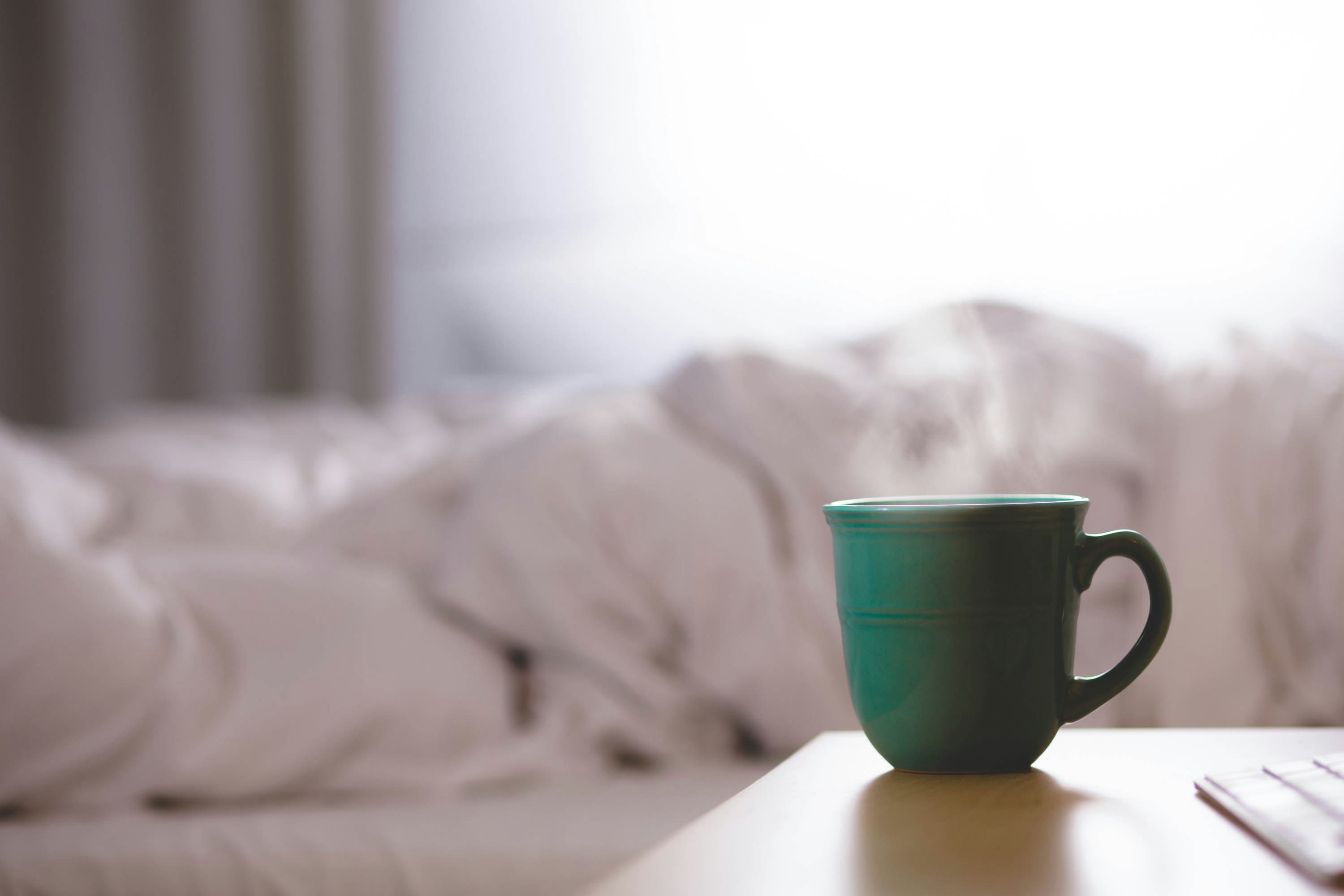 green ceramic mug on wooden desk