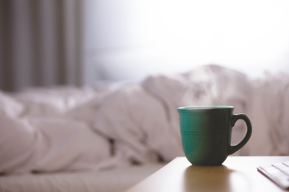 Taza de cerámica verde sobre escritorio de madera