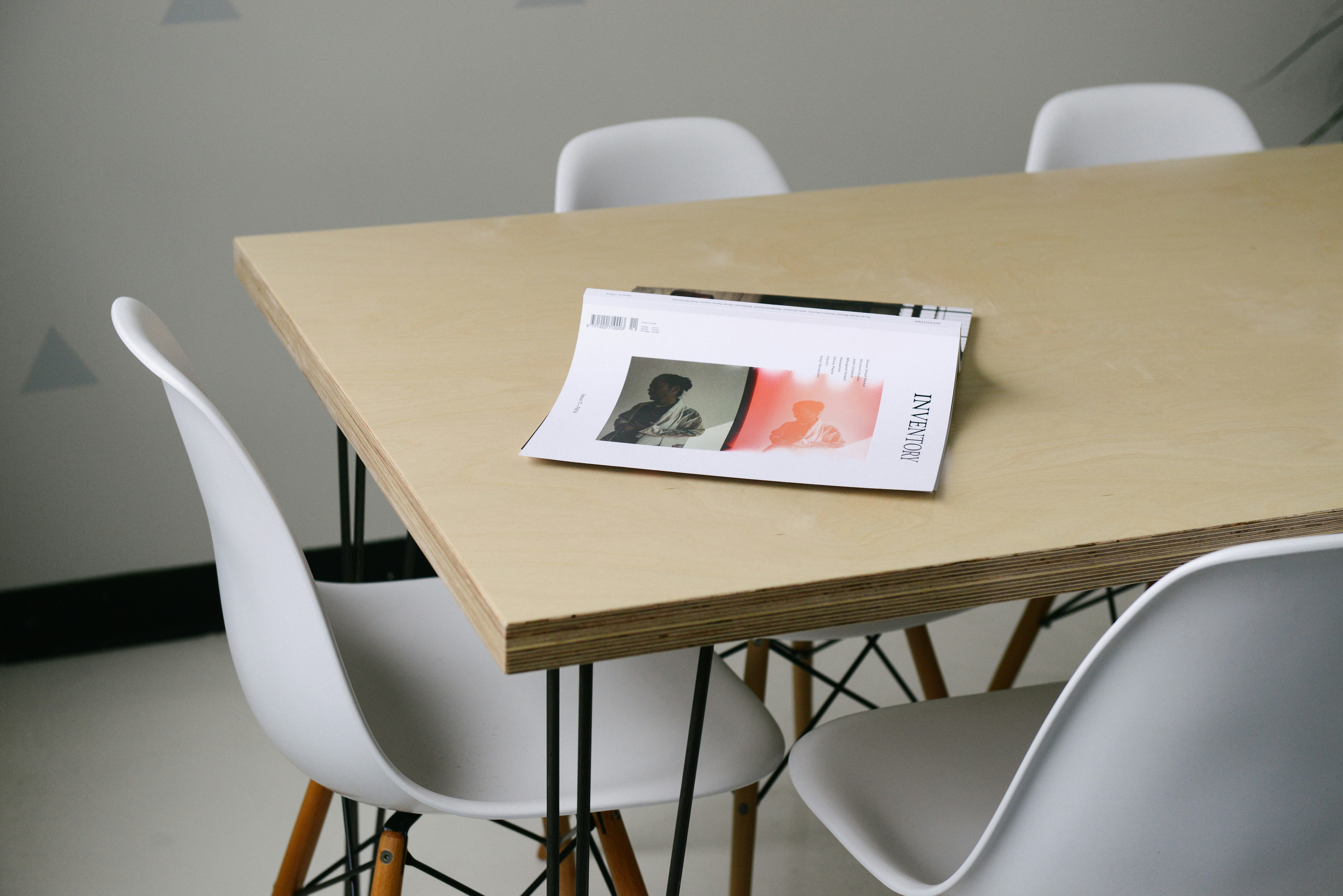 A business book turned over on a wooden table surrounded by chairs in a simple office setting