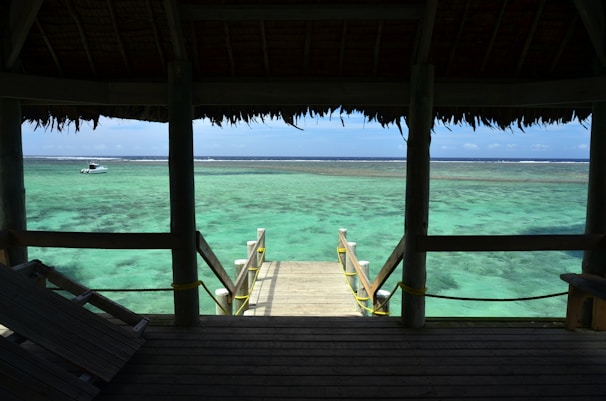 Sunlit beachfront villa with wooden deck overlooking turquoise ocean.