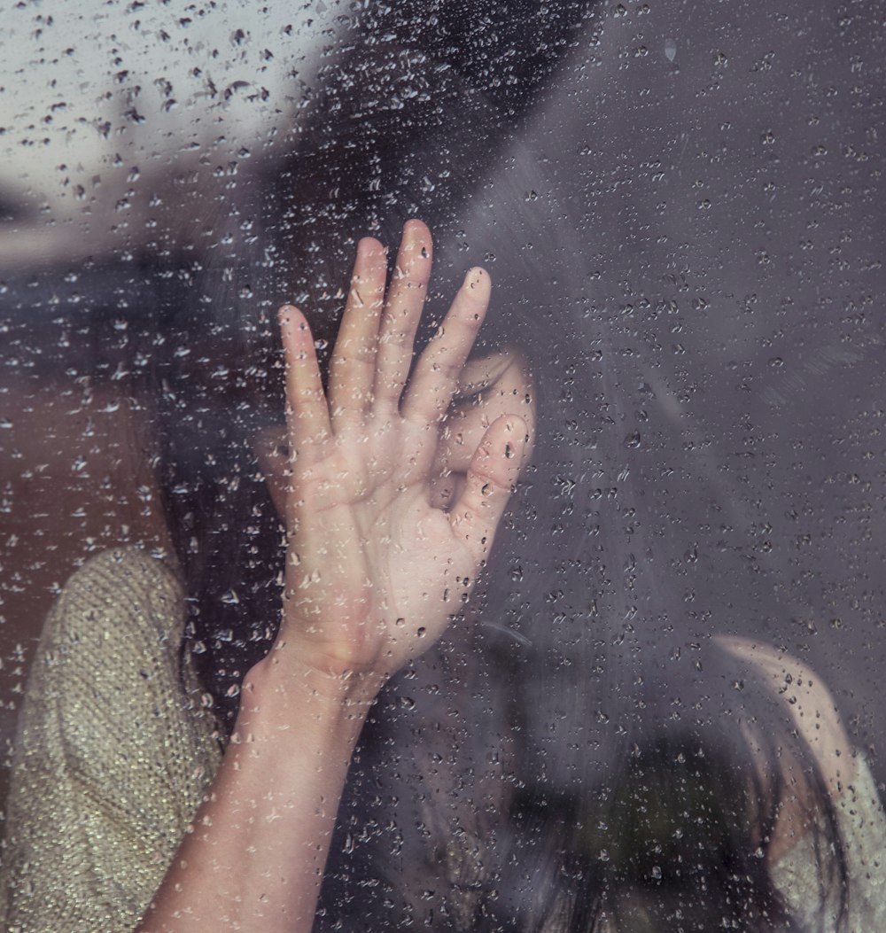 woman touch rainy glass