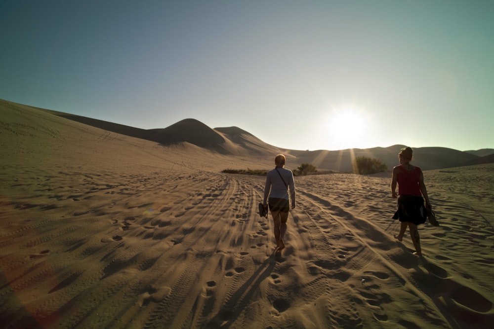 昼間、砂の上を歩く2人の女性