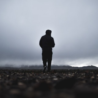 silhouette of person walking in front of mountain