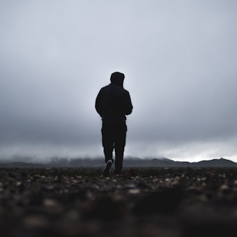 silhouette of person walking in front of mountain