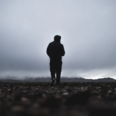 silhouette of person walking in front of mountain