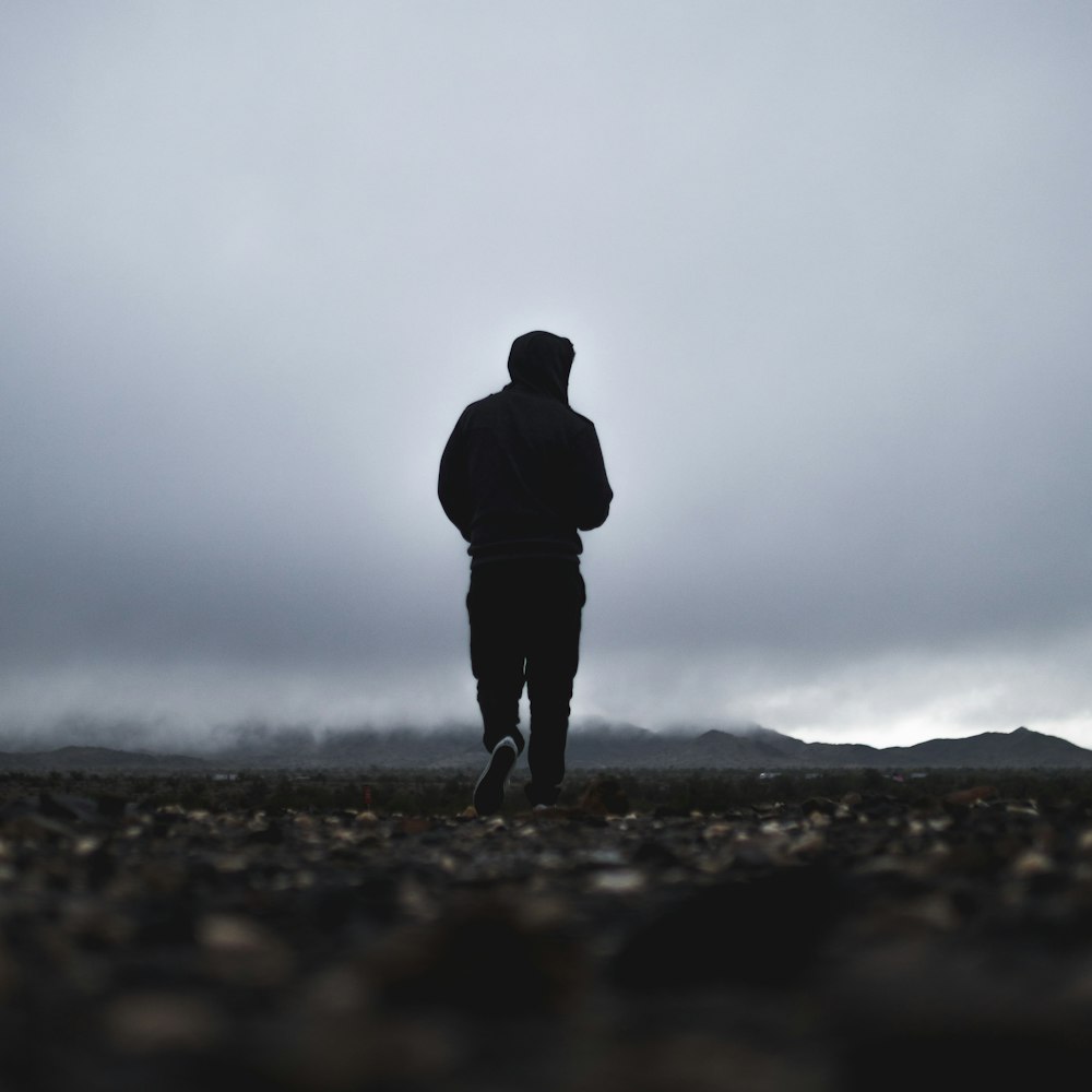 silhouette of person walking in front of mountain