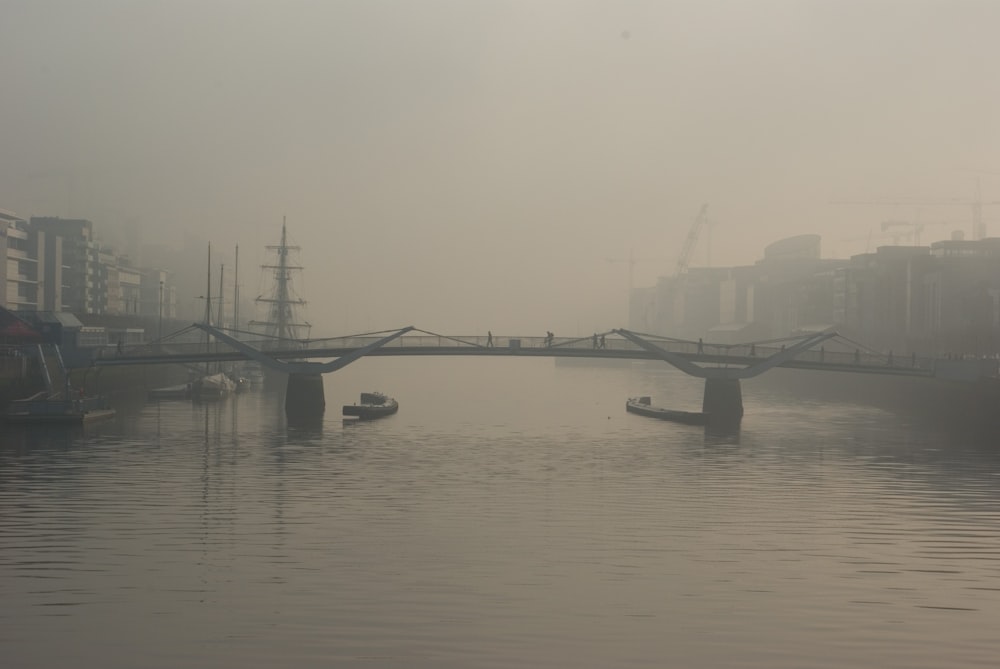 two boats below bridge with fogs