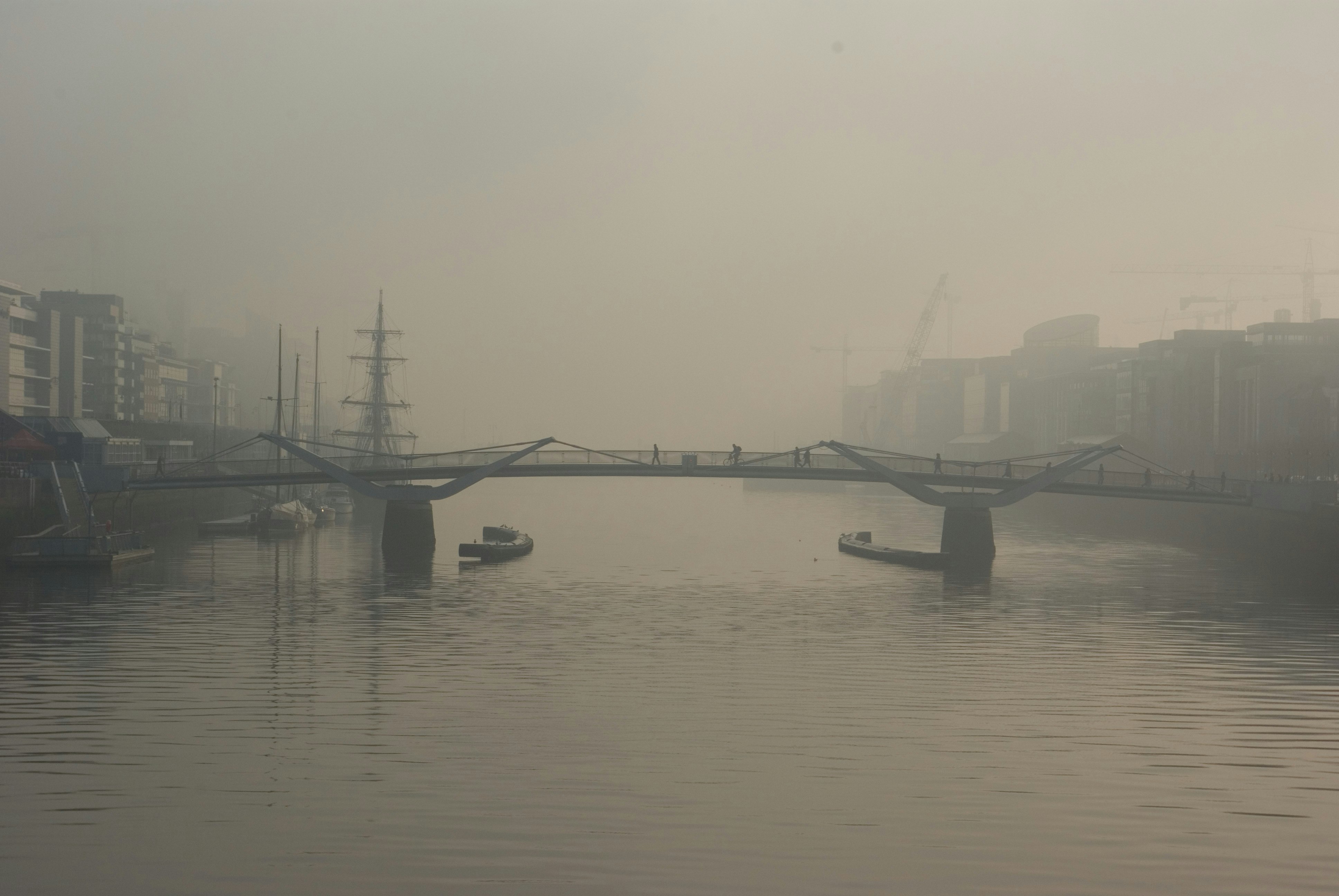 two boats below bridge with fogs