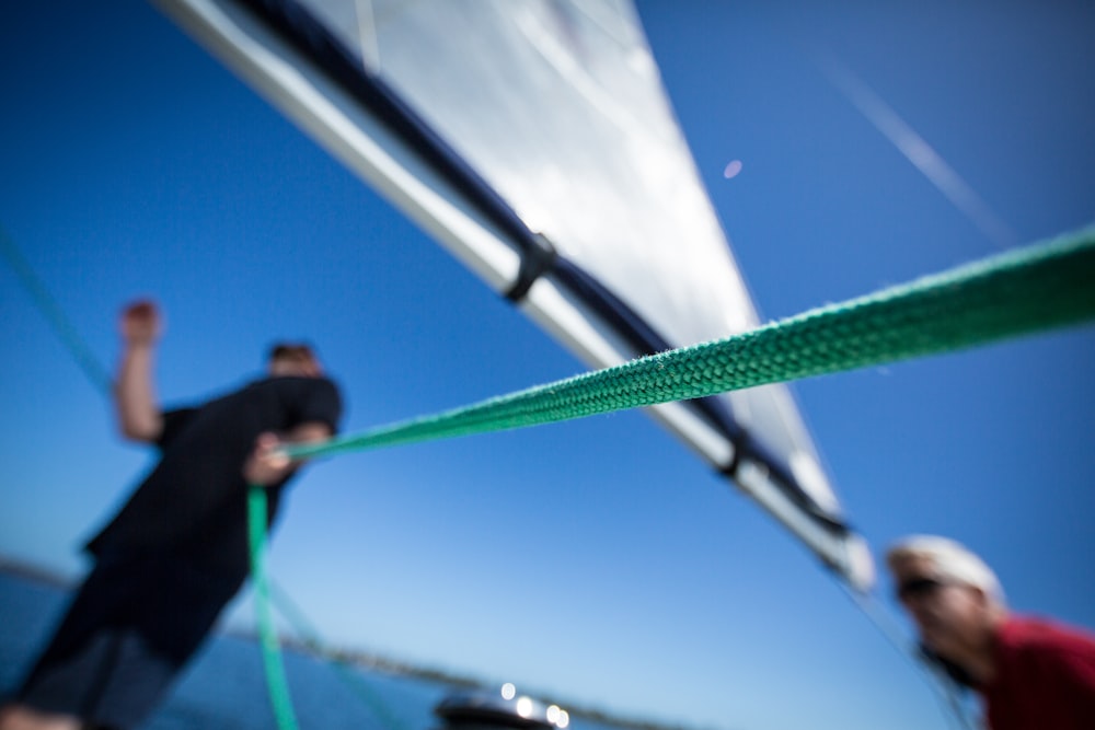 person holding green rope near boat sail