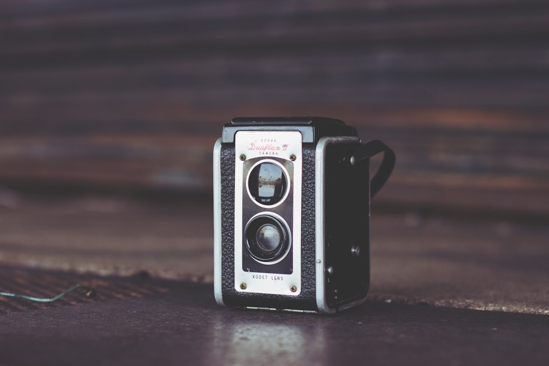 focus photo of black and gray vintage camera on brown surface