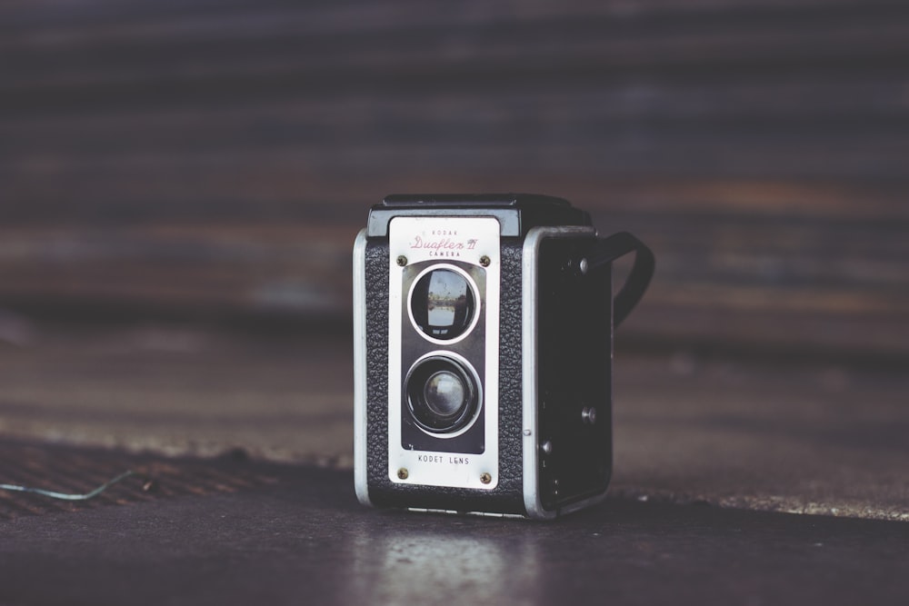 focus photo of black and gray vintage camera on brown surface