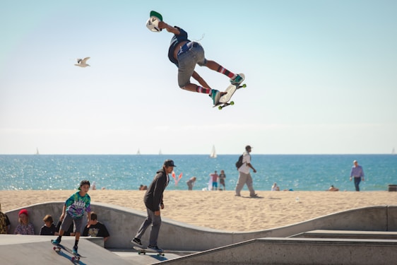A cheerful instructor helping a young student balance on a skateboard against the backdrop of Taghazout’s coastline.