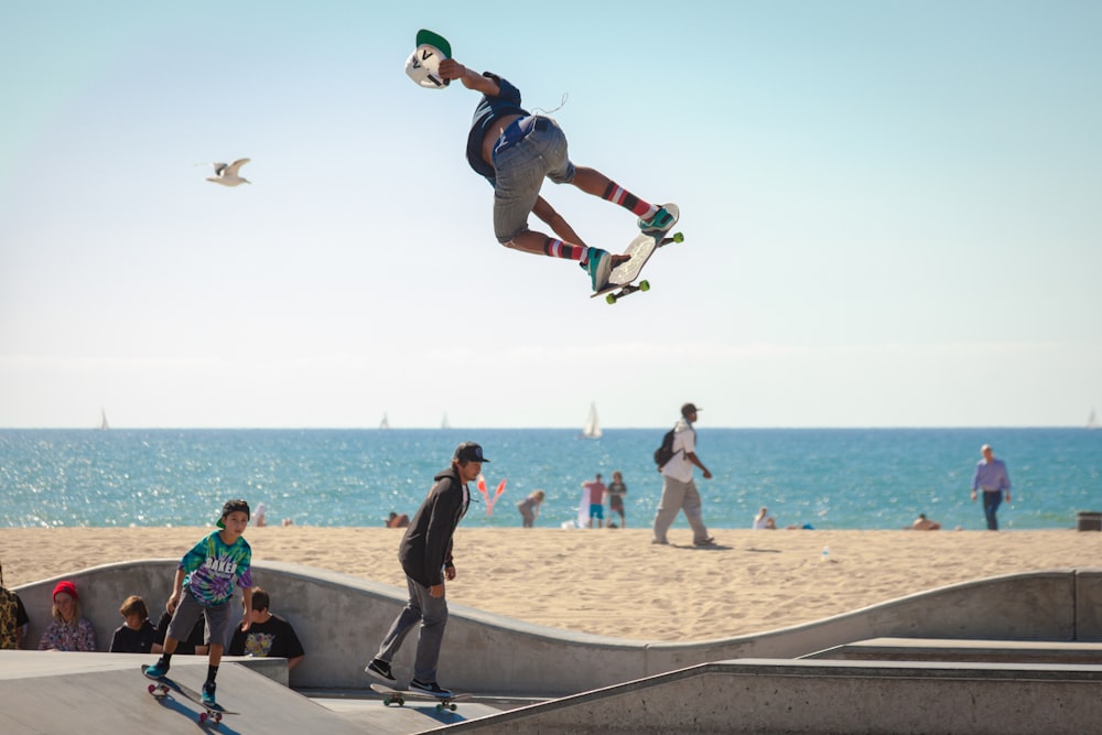 three people playing skateboard beside seashore during daytime