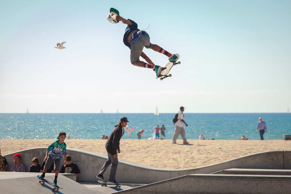 três pessoas jogando skate ao lado da praia durante o dia