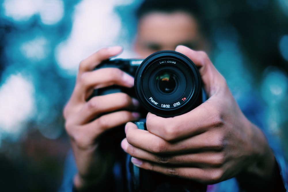 pessoa segurando câmera DSLR preta