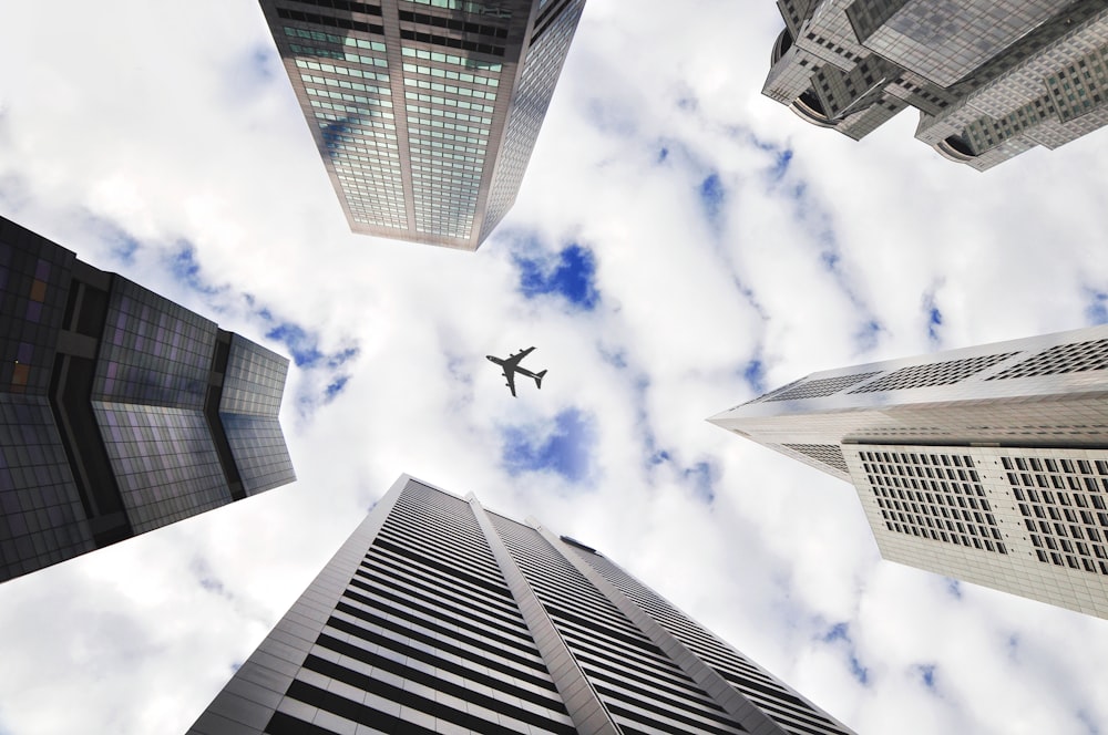 low-angle photo of five buildings with airplane in the middle of picture