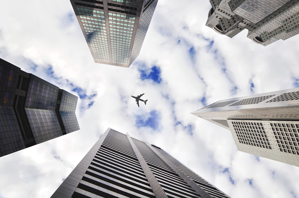 Foto de ángulo bajo de cinco edificios con avión en el centro de la imagen