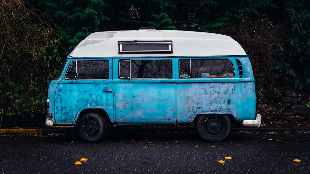 van azul e branca estacionada perto da árvore verde