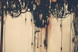 Various audio cables are hanging down, with a focus on numerous jack plugs extending from the coiled wires. The background is a soft, neutral tone, providing contrast to the dark cables.