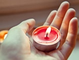 A close-up of a hand pouring wax into a candle mold.