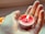 A close-up of hands holding a lit candle with herbs.