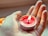 A close-up of hands holding a lit candle with herbs.