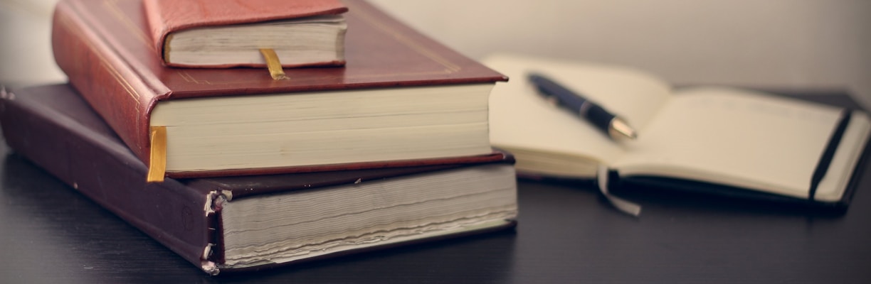 selective focus photography of three books beside opened notebook