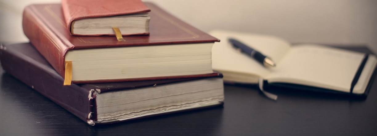 selective focus photography of three books beside opened notebook